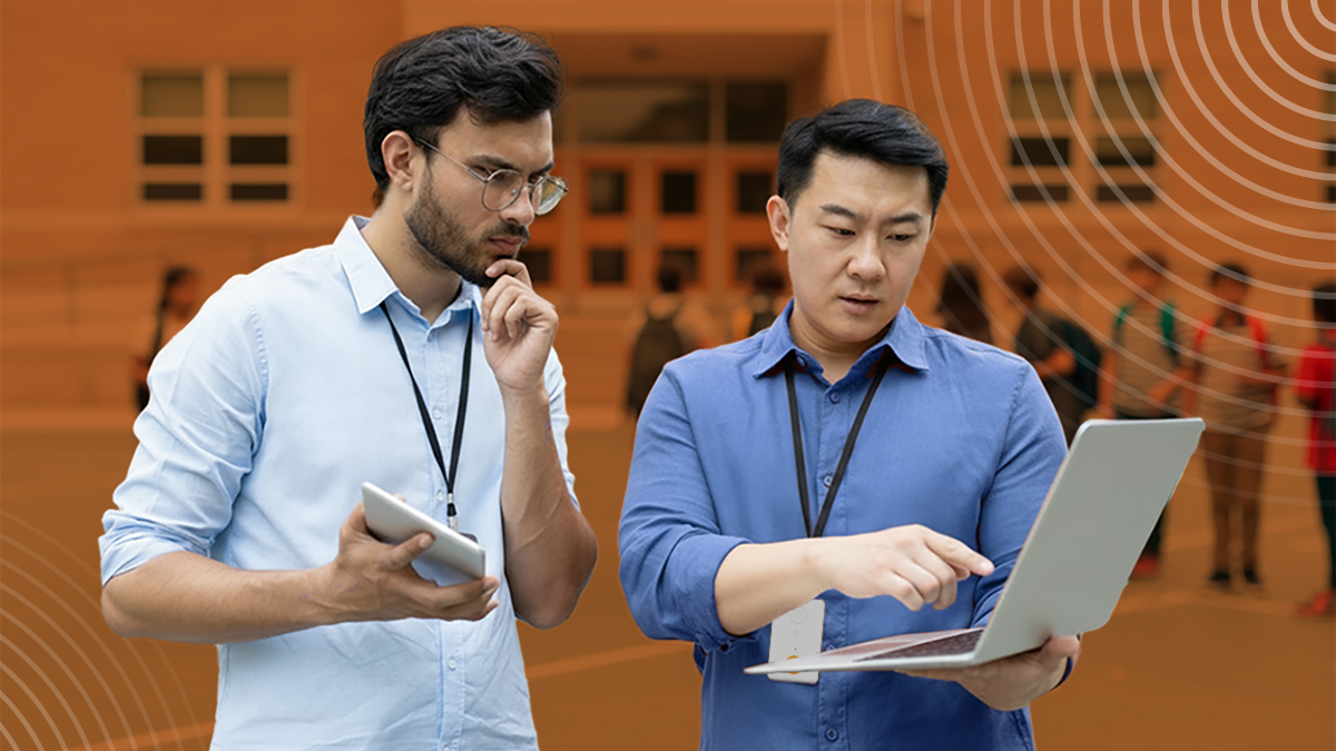 Image of two men wearing Raptor badges reviewing risk and threat assessment on a laptop outside of a school.