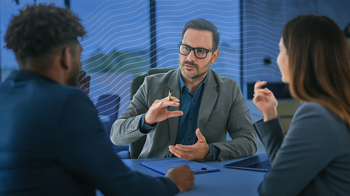 A man speaking two another man and woman during a behavioral threat assessment team meeting at a school