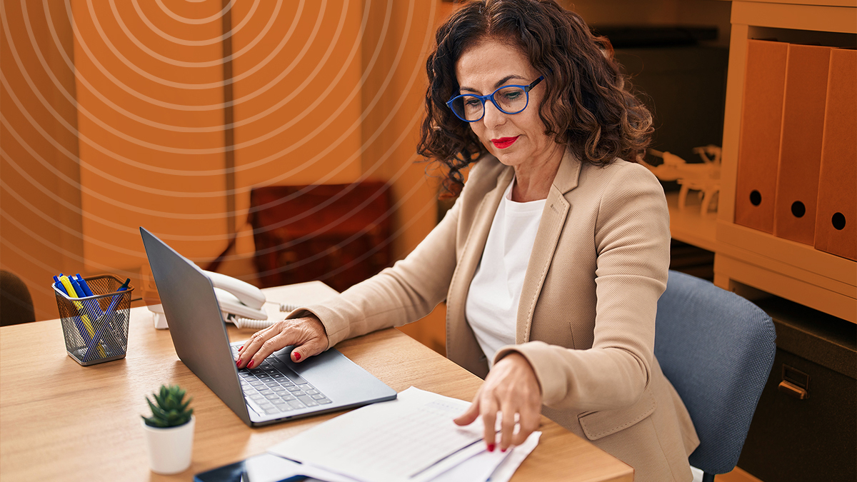 A woman working on a laptop and looking at papers as she applies for an SVPP grant