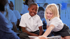 Private school students wearing uniforms sitting and reading together.