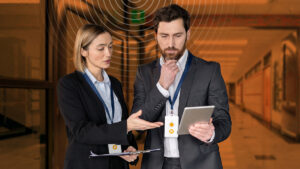 A man and woman, both school administrators, look at a tablet and review their school emergency management software: Raptor Technologies