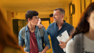 A teacher gives guidance to a young man in a hallway as part of PBIS strategies