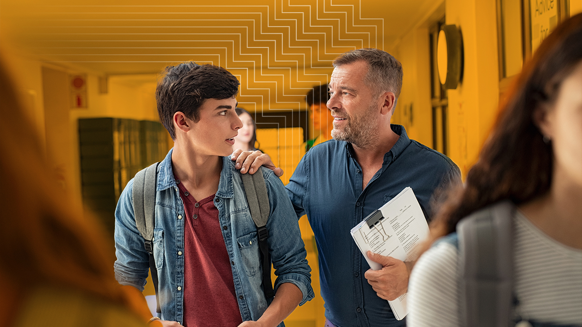 A teacher gives guidance to a young man in a hallway as part of PBIS strategies