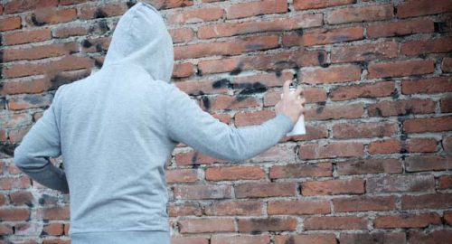 Student vandalizing wall with graffiti