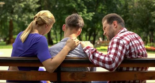 parents comforting teenage son